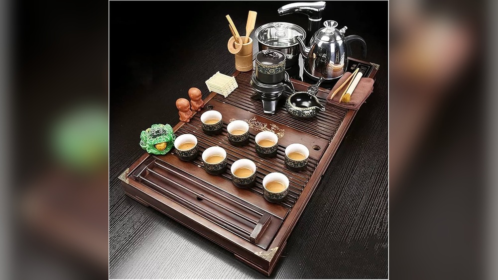 Elegant Chinese tea ceremony set with teapot, cups, and accessories on a wooden tray.