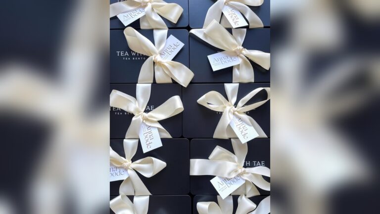 Elegant black gift boxes with cream ribbon bows, some with "Anna Bode" tags.