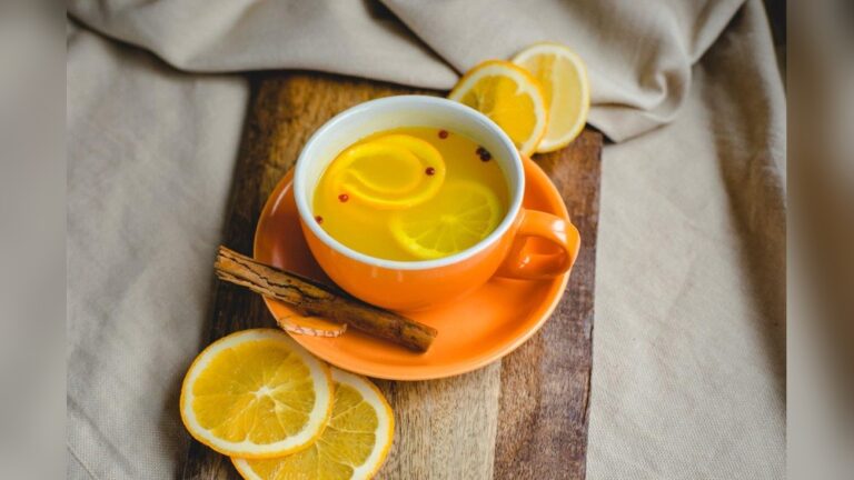 Orange cup of immunity boosting tea with orange slices and cinnamon stick