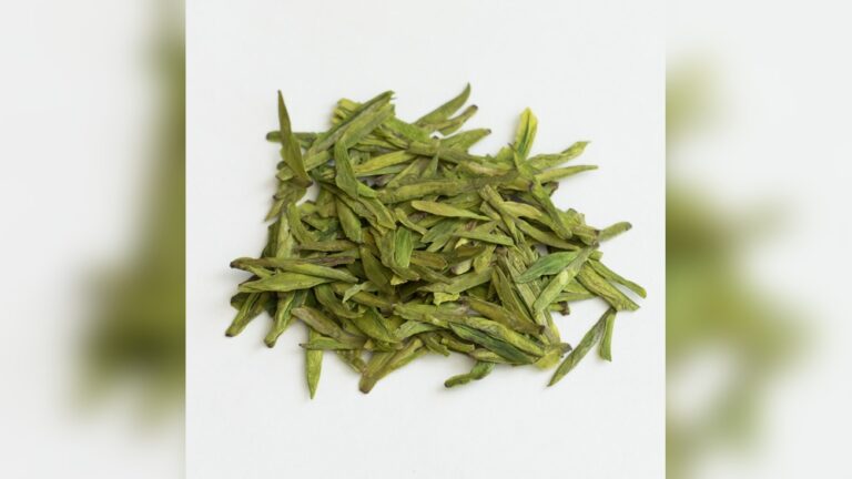Dried Longjing green tea leaves, known for their flat, sword-like shape.