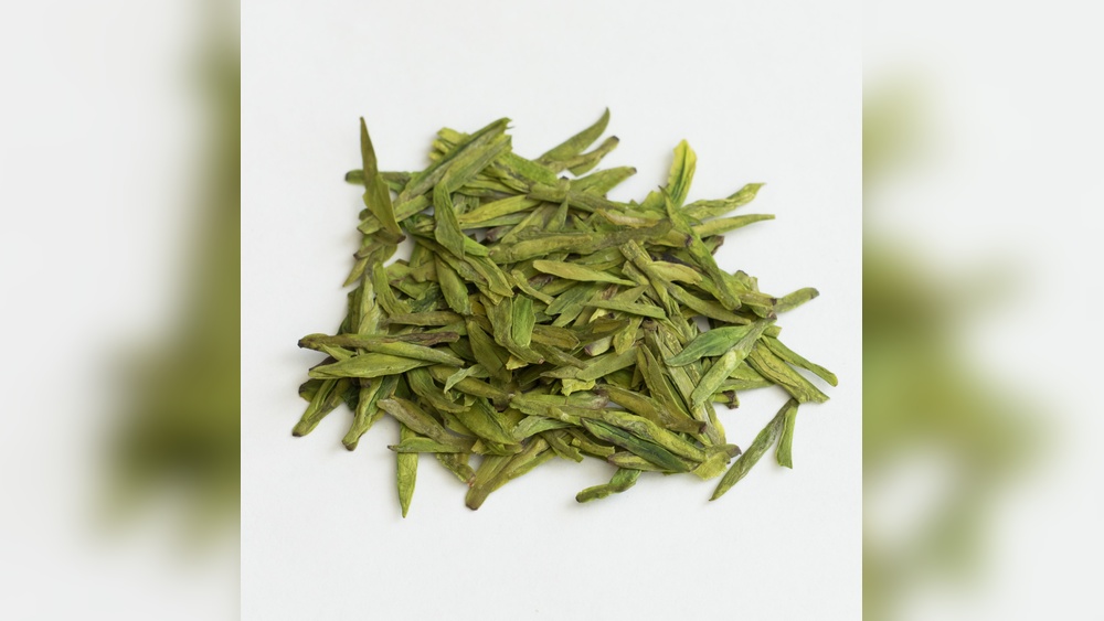 Dried Longjing green tea leaves, known for their flat, sword-like shape.
