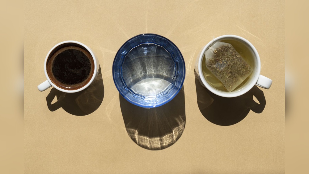 Coffee, water, and tea in cups and glass, illustrating drinking coffee and tea in the same day.